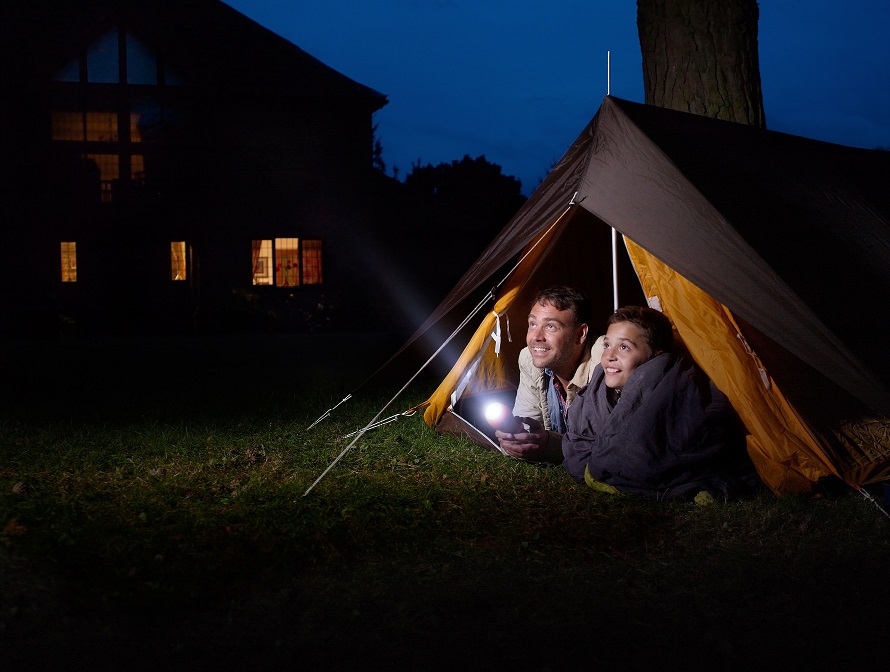 couple in tent with flashlight camping in their yard