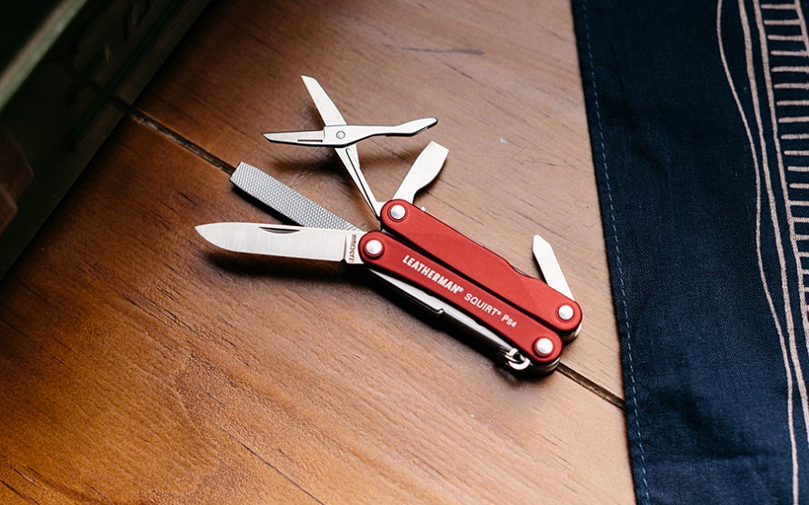 picture of Leatherman Multitools on a wooden desk beside a peace of material