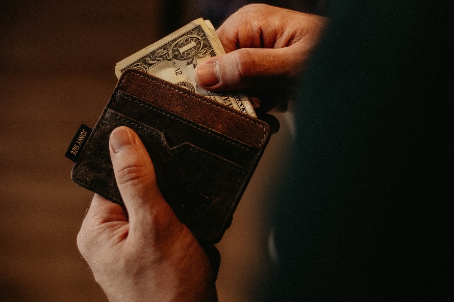 picture of man getting money from a brown minimalist pocket wallet