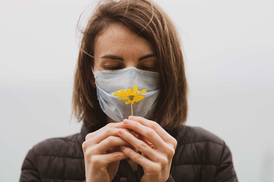 picture of a woman with mask and a flower in front her nose