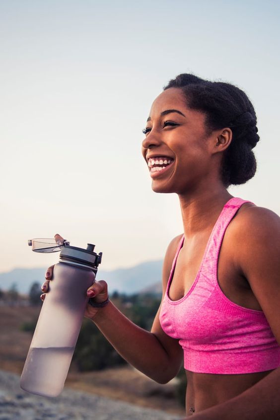 woman smiling and holding a water bottle