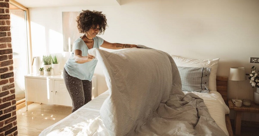 woman folding sheets on bed