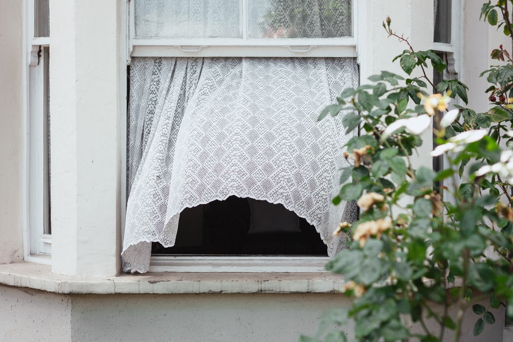 Open window on a house with white curtains