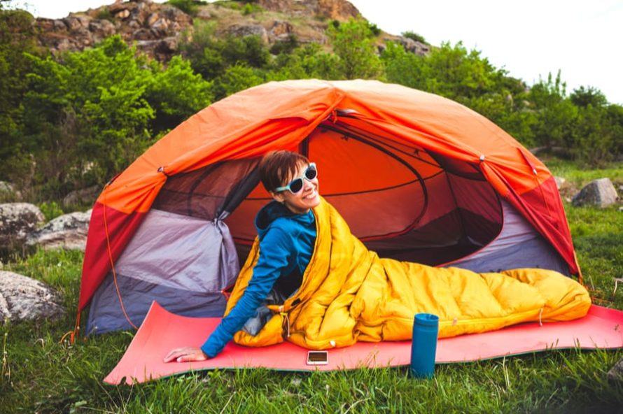 Woman in a Sleeping Bag for Camping in front of a tent