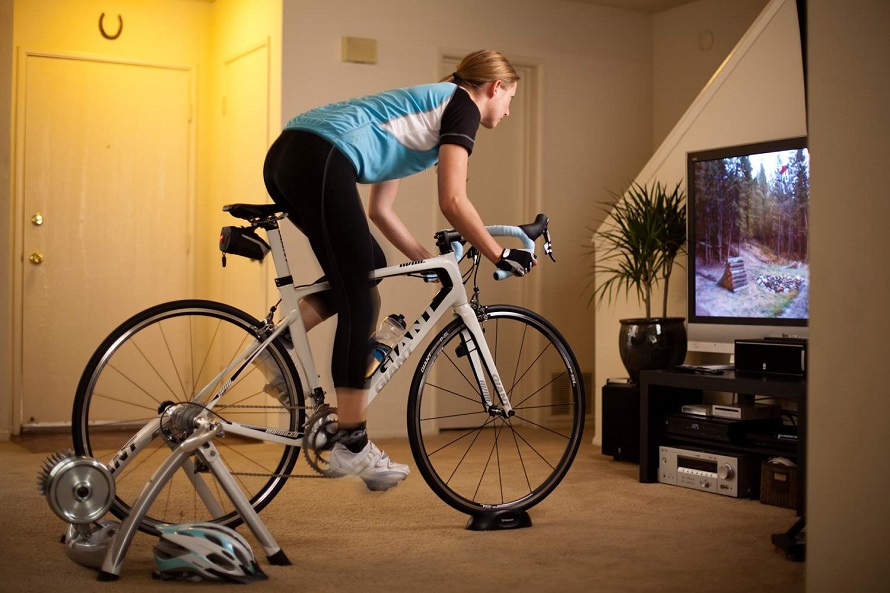 woman riding bike with a n indoor turbo trainer and watching TV  