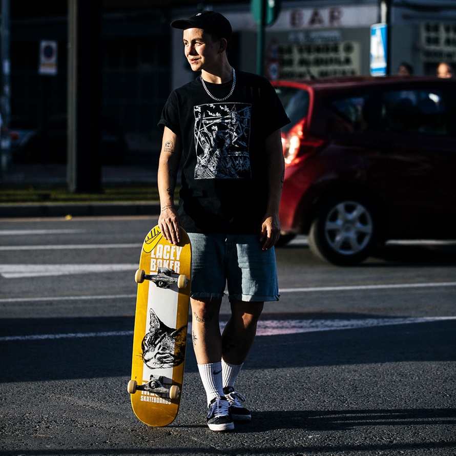 skater holding his skateboard walking across the road