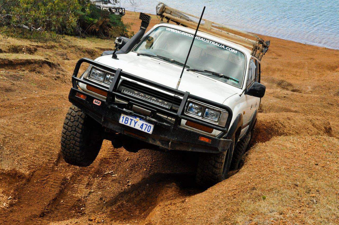 Four-wheel drive vehicle navigating rough off-road terrain with one wheel elevated.