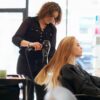 Hairdresser blow-drying a woman's hair in a salon.