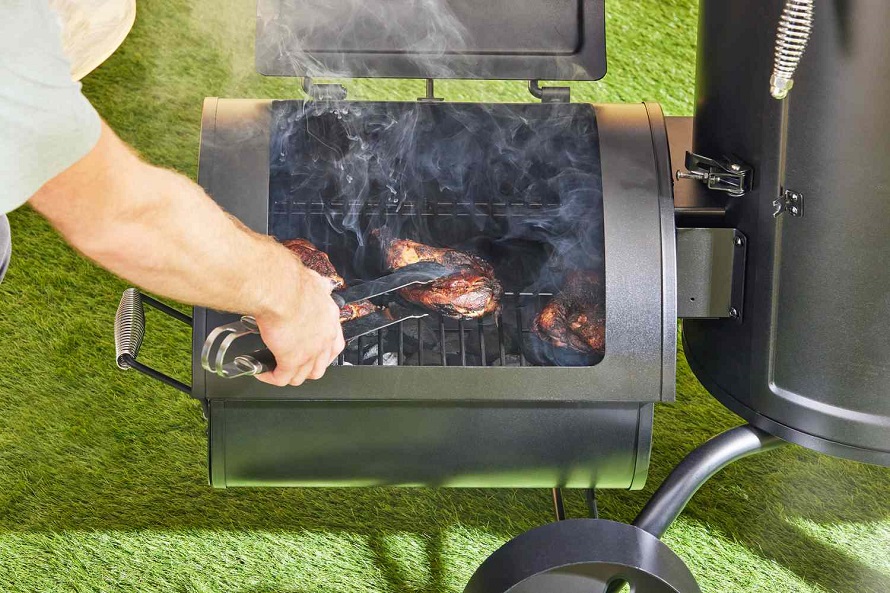 person flipping the meat on the barbeque smoker